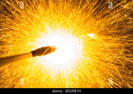 Makroaufnahme von hellen goldenen Funken, die von einem brennenden Funken oder Pyrotechnik auf schwarzem Hintergrund fliegen Stockfoto