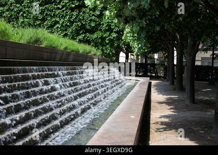 Stufenwasserspiel und schattige Bäume am Cabot Square Plaza, Canary Wharf, schaffen eine ruhige urbane Oase im Londoner Finanzviertel. Stockfoto
