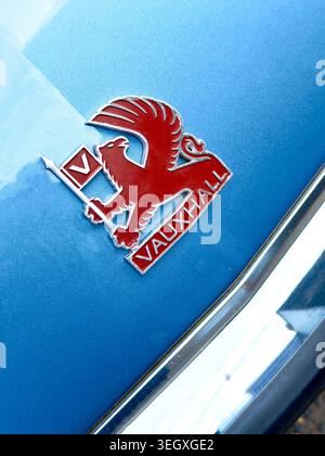Nahaufnahme eines alten roten Vauxhall griffin Emblems auf einer metallischen blauen Motorhaube Stockfoto