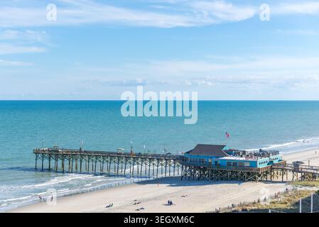 Myrtle Beach Pier aus einem erhöhten Winkel an einem sonnigen Frühlingstag. Das Meer hat einen wunderschönen Blauton unter einem blauen, teilweise bewölkten Himmel. Stockfoto