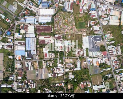 Vertikale Draufsicht der Drohne von oben auf eine gemischte Landschaft mit Fabriken, Ackerland und Wohngebieten im Bezirk Cu Chi, Ho Chi Minh City Stockfoto