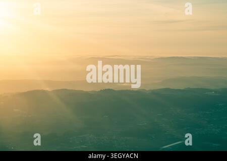 Ein atemberaubendes Passagier-POV-Foto aus einem Flugzeugfenster während eines Fluges in der Abenddämmerung. Die dramatische Landschaft zeigt die klare Silhouette des Stockfoto