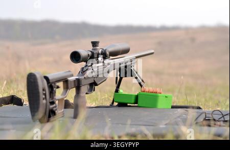 Modernes Präzisions-Scharfschützengewehr mit optischem Oszilloskop auf Zweibeinstativ am Schießstand Stockfoto