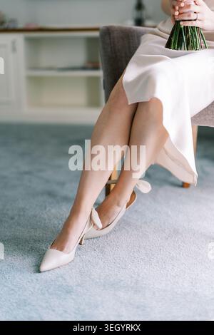 Braut Sitzt Drinnen Und Hält Hochzeitsstrauß Stockfoto