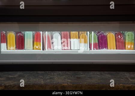 Eine farbenfrohe Reihe von handgewickelten Eispops und Fruchtkaffeln in einem Kühlglasfenster in einem lokalen Dessertgeschäft. Stockfoto