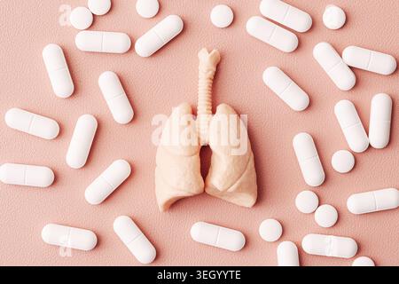 Menschliches Lungenmodell umgeben von weißen Pillen Nahaufnahme. Respiratorische Versorgung und pharmazeutisches Behandlungskonzept auf rosa Hintergrund. Stockfoto
