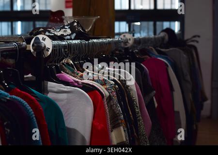 Kleiderreihen hängen an Regalen in einem Second-Hand-Geschäft, in denen Second-Hand-Mode, Einzelhandelsgeschäfte und organisierte Bekleidungsausstellungen gezeigt werden Stockfoto