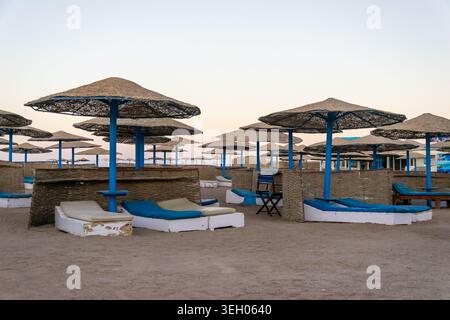 Reihen von Strohschirmen und Liegestühlen an einem Sandstrand Stockfoto