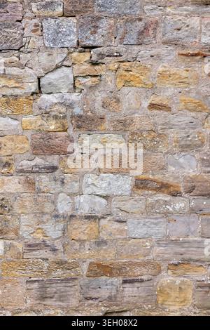 Verwitterte Steinmauerstruktur mit gemischten Sandsteinblöcken und Mörtel aus einem alten Gebäude außen, geeignet für Architektur und Hintergrund Stockfoto