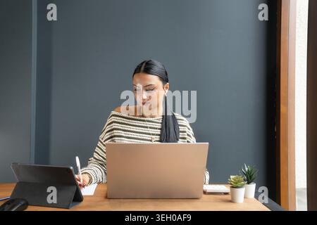 Porträt eines fokussierten jungen Profis, der an einem Laptop an einem sauberen und modernen Arbeitsplatz arbeitet. Geeignet für Unternehmen, Bildung und Fernarbeit Stockfoto