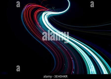 Abstrakte rote und blaue Lichtbahnen mit eleganten Kurven auf Schwarz Stockfoto