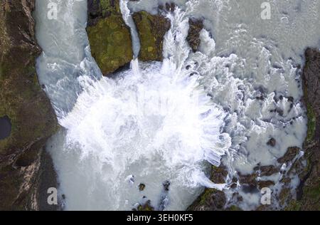 Blick aus der Vogelperspektive auf den Godafoss Wasserfall mit mächtigem Wildwasser, das über dunkle vulkanische Felsen und moosige Klippen stürzt, Thingeyjarsveit, Island. Stockfoto