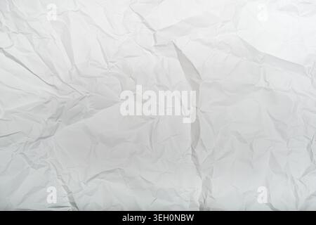 Helle weiße zerknitterte Papierstruktur mit weichen Falten, hellen Schatten und einem sauberen minimalen Look für neutrale Designhintergründe. Stockfoto