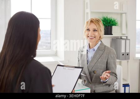 Zwei weibliche Kollegen diskutieren Projekte am Bürotisch und tauschen Ideen aus, während sie zusammenarbeiten. Stockfoto