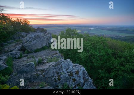 Blick auf Havrania Skala in den männlichen Karpaty Bergen mit felsigen Klippen und üppigen grünen Wald unter einem farbenfrohen Sonnenuntergang Himmel Smolenice, Trnava Region, Slo Stockfoto