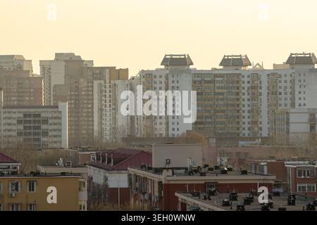 Blick auf die hohen Wohnhäuser und die Dächer der Stadt unter einem trüben goldenen Himmel Peking, Peking, China. Stockfoto