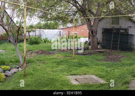 Traditionelles ländliches Haus mit grünem Garten Rasen und Bäumen in ruhigem ländlichem Dorf Stockfoto