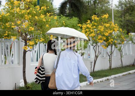 Weibliche Touristen, die einen Schirm halten und zusammen laufen, Touristen, die durch lokale städtische Atmosphäre laufen, Rückansicht. Stockfoto