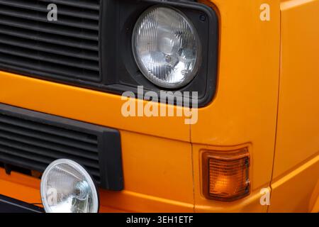 Nahaufnahme eines alten orangen Autos von vorne mit schwarzem Kühlergrill und runden Scheinwerfern Stockfoto