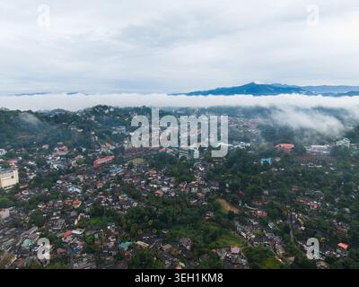 Blick aus der Vogelperspektive auf Kandy City mit dichten Wohngebäuden, üppigem tropischem Grün und niedrig hängendem Nebel über den umliegenden Bergen Kandy, Central Stockfoto
