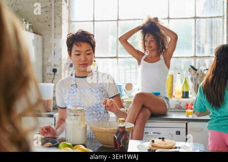 College, Studentenwohnheim und Freunde in der Küche zum Frühstück, Essen und bereiten Pfannkuchen am Morgen zusammen. Wohnung, Studenten und Frauen mit Zutaten für Stockfoto