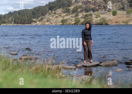 Frau, die auf Felsen im ruhigen Bergsee steht Stockfoto