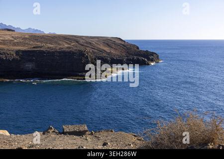 Tiefblaues Atlantikwasser unter dramatischen Vulkanklippen in der Nähe von Agaete, Gran Canaria, Kanarischen Inseln, Spanien. Stockfoto