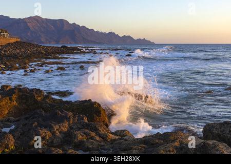 Ozeanwellen brechen gegen schwarze Vulkangesteine an der Küste von Agaete, Gran Canaria, Kanarischen Inseln, Spanien. Stockfoto