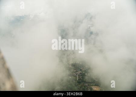 Blick auf das Tal unten durch dicke weiße Wolken und Nebel vom Ambuluwawa Tower in Gampola, Zentralprovinz, Sri Lanka. Stockfoto