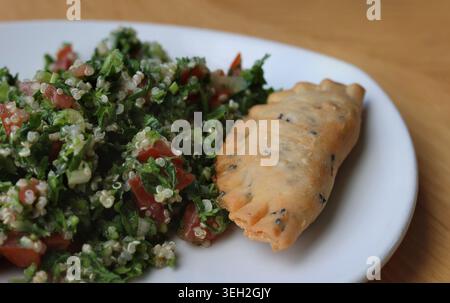 Ein Palte von Tabbouleh mit Quinoa und einem frittierten Käse Sambousek. Stockfoto