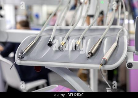 Zahnärztliche Instrumente auf dem klinischen Behandlungstisch. Nahaufnahme zahnärztlicher Handstücke und Saugwerkzeuge auf einem Tablett in einer modernen Zahnarztpraxis. Stockfoto