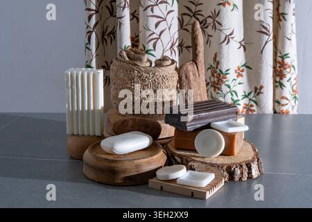 Sammlung natürlicher Seifenstangen auf Holzpodien mit rustikalen Badaccessoires und Öko-Dekor. Eine Auswahl an Seifen und Loofah Stillleben Stockfoto