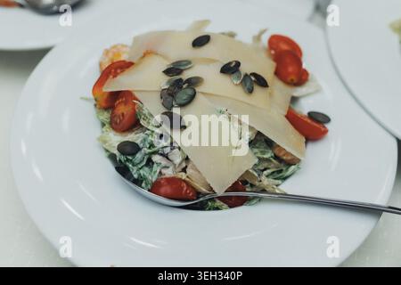 Frischer Salat mit Tomaten, Kürbiskernen und geriebenem Käse Stockfoto