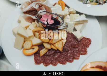 Käseplatte kunstvoll mit Crackern und Wurstwaren arrangiert Stockfoto