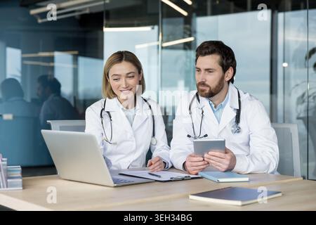 Ärzte prüfen Patientendaten und Patientenakten, nutzen moderne Technologie für effizientes Gesundheitsmanagement und professionelle medizinische Beratung im Klinikumfeld Stockfoto