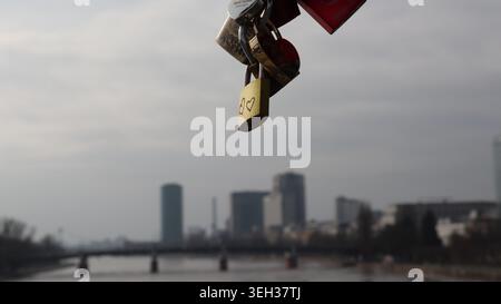 Redaktionelle Nahaufnahme romantischer Liebesschlösser, die an der Eisernen Steg-Fußgängerbrücke befestigt sind, mit Blick auf den Main und die Stadtsilhouette von Frankfurt Stockfoto