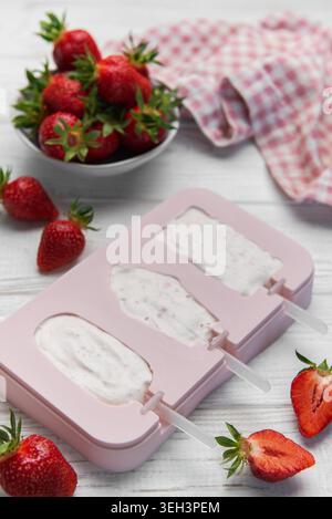 Rosafarbenes Schimmeltablett mit cremiger Dessertmischung und frischen Erdbeeren auf hellem Hintergrund Stockfoto