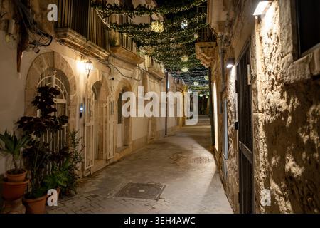 Eine charmante, enge Straße in Ortigia, Sizilien, wunderschön dekoriert mit Weihnachtsmärchen und glühenden Ornamenten. Die historische Steinfassade Stockfoto