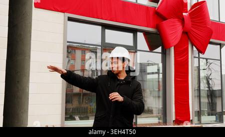 Mann mit weißem Schutzhelm, der auf etwas im Freien zeigt Stockfoto
