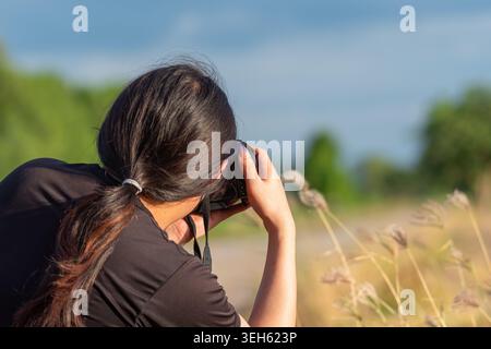 Junge Frau, die während der goldenen Stunde mit der Kamera im Freien fotografiert, um Naturreisen und kreative Lifestyle-Momente festzuhalten Stockfoto
