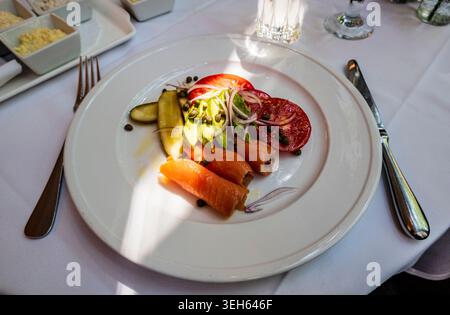 New York, NY - USA - 16. Mai 2026 Eine lebendige Platte mit gerolltem Räucherlachs, frischen Avocadoscheiben, Reifen Tomaten, roten Zwiebeln, Kapern, und Gurke Stockfoto
