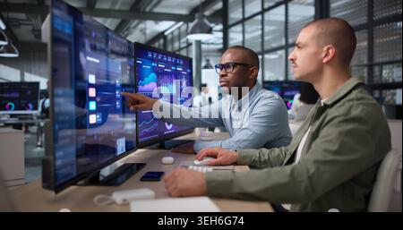 Zwei Junge Datenanalysten Prüfen Financial Dashboard Auf Dem Computerbildschirm. Stockfoto