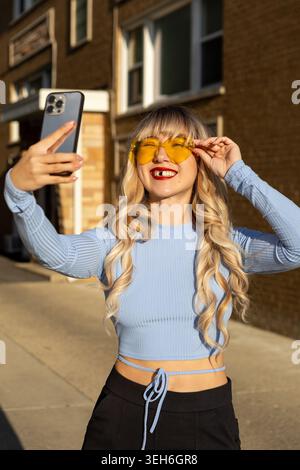 Eine Frau steht draußen und lächelt weit, um zu zeigen, dass ihr ein Vorderzahn fehlt. Sie wirkt emotional und betont ihren Zustand. Die Sonne ich Stockfoto