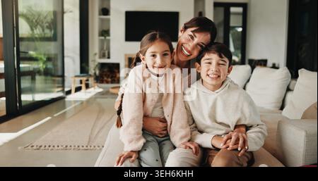 Porträt, Mutter oder Kinder mit Umarmung im Wohnzimmer, Glück oder Unterstützung für die Sicherheit von Beziehungen. Umarmen, Frau oder Kinder mit einem Lächeln für emotionale Gefühle Stockfoto