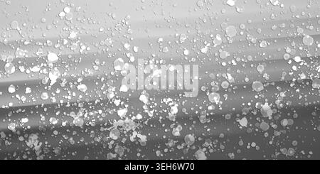Ein künstlerischer abstrakter Hintergrund mit einem glatten, monochromatischen Grauverlauf, überlagert mit verstreuten weißen Farbspritzern und Punkten. Stockfoto