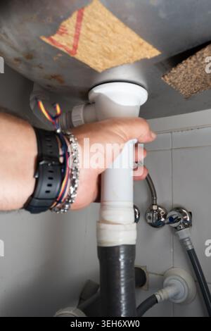 Eine neue P-Falle-Leitung von Hand unter einem Spülbecken anschließen Stockfoto