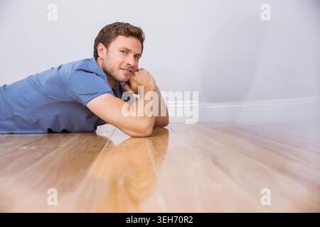 Der polierte Hartholzboden reflektiert schwache Formen im leeren Innenraum mit weißer Grundplatte. Mann, Ruhe, Minimalismus, Hochglanz, Holz, Raum, hell Stockfoto