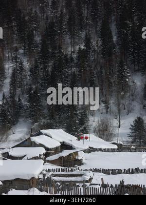 Snow Village Blockhütten in der Winterszene des Evergreen Forest Stockfoto