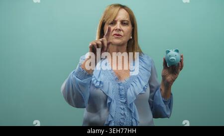 Frau mit blauem Schweinebanken-Finger im Studio mit sichtbarem Zeigefinger und ernstem Ausdruck, direktem Blick und erhobener Hand; Sparratschlag ste Stockfoto
