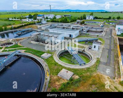 Eine große Wasseraufbereitungsanlage verarbeitet Abwasser in einer grünen Landschaft. Tanks und Geräte sind sichtbar und zeigen die Schritte der Wasserreinigung. Stockfoto